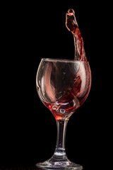 a splash of red wine in a glass on a black background