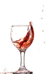 a splash of red wine in a glass on a white background