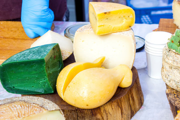 mix of various varieties of hard cheese on a wooden board. View from above.