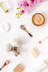 Massage table with thai herbal balls and orchids on white background top view pattern