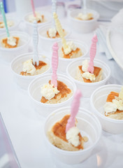 Food free sample. A small bite piece of souffle pancakes with fresh cream in small plastic takeaway cup for customers to try. Soft focus on the pancake with pink toothpick.