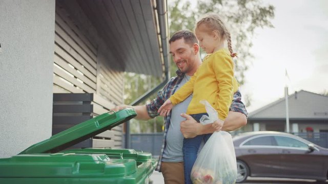 Happy Father Holding a Young Girl and Going to Throw Away an Empty Bottle and Food Waste into the Trash. They Use Correct Garbage Bins Because This Family is Sorting Waste and Helping the Environment.