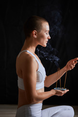 Attractive woman in white clothes inhales smoke from candle. Healthy lifestyle