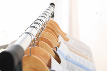 Hangers with shirts against light background, space for text