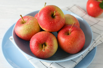 Composition with plate and apples on white wooden background, close up