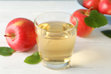 Apples and glass with juice on wooden background, space for text