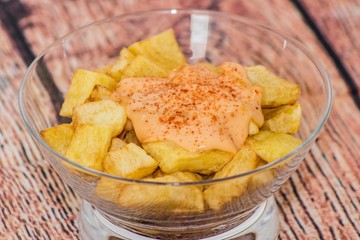 Plate of spanish potatoes with spicy sauce on a glass container