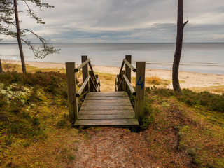 Wooden steps to sandy beach, Jurmala region, Latvia, Gulf of Riga, cloudy sky over water surface.