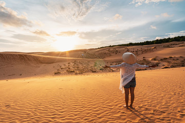 Young woman traveler looking sunset at red sand dunes in Vietnam, Travel lifestyle concept