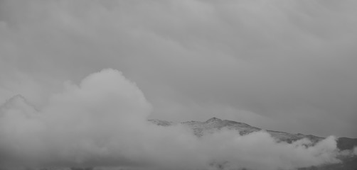 Morning view of Sierra Nevada between clouds covered by the first snowfall of autumn