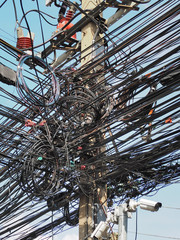 Many electrical cable, wire, telephone line and CCTV on electricity pole, The chaos of cables and wires on every street in Bangkok, Thailand.
