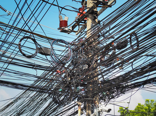 Many electrical cable, wire, telephone line and CCTV on electricity pole, The chaos of cables and wires on every street in Bangkok, Thailand.