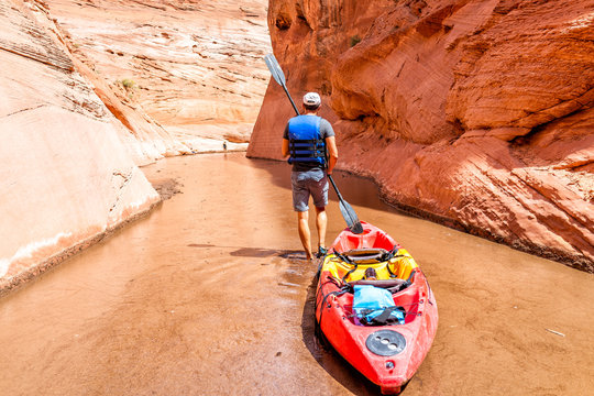 Kayaking Trail In Lake Powell Narrow Antelope Canyon With Man Walking Holding Paddle Oar Dragging Kayak Boat To Deeper Dirty Muddy Water