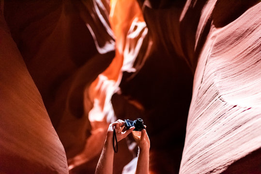Hands arms holding camera up in upper Upper Antelope slot canyon in Arizona person people taking pictures of red rock formations