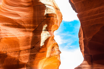 Abstract view of blue sky and clouds framing by narrow Upper Antelope slot canyon in Page, Arizona with bright orange color on sandstone formations - Powered by Adobe