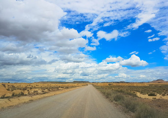 Fototapeta na wymiar Gravel road across the Spanish desert Bardenas Reales in the southeast of Navarre