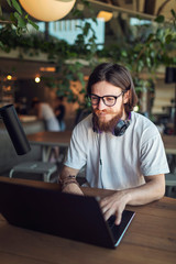 Cheerful male freelancer with beard and moustache working in a loft workspace