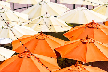 Many colorful yellow orange umbrellas high angle aerial bird's eye closeup view at cafe or...