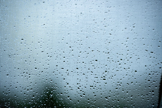 Raindrops on a mosquito net. Mosquito net on a window with a curtain. Horizontal photo, macro.