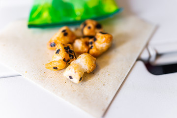 Japanese snack food on airplane flight with salty nori rice crackers on green tea napkin and packaging