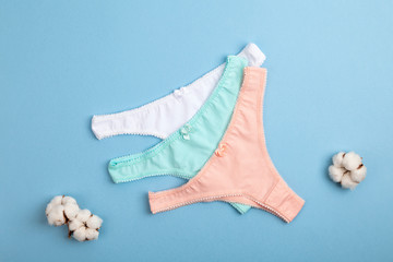 Female pastel cotton set panties and cotton flower on blue background. Beautiful lingerie. Top view, flat lay. Women's natural underwear. 