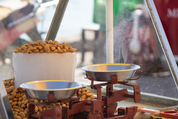 Cold almonds are sold in the open space in the bench. Ice and almonds stacked on top. Weighing on the balance.