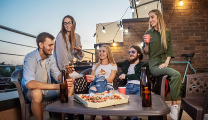 Best friends having Friday beer and pizza on a terrace lit by sunset sun - obrazy, fototapety, plakaty