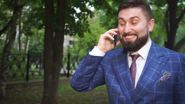 handsome man with brown thick beard speaks on smartphone