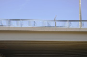 Fototapeta premium Close - up of a concrete bridge, against the blue sky, side view. Visible railing.