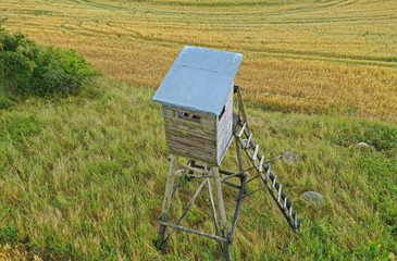 Perspective aerial drone view on wooden hunting tower in fields and meadows surroundings