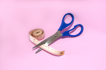 Scissors cutting tape measure isolated on pink background. Concept of work lifestyle, sewing...
