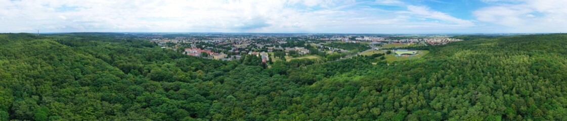 Aerial drone wide panoramic view on green lungs forest surrounding european city during summer, aquapark complex