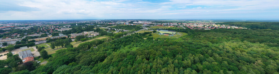 Fototapeta na wymiar Aerial drone wide panoramic view on green lungs forest surrounding european city during summer, aquapark complex