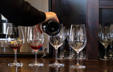 Woman Pouring Red Wine Into Four Crystal Glasses for A Wine Tasting