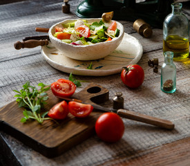 salad with sliced cucumbers, tomatoes, salad leaves, mozzarella cheese in ceramic bowl