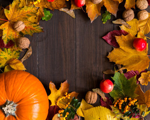 Dynia z liśćmi, orzechami, jarzębiną i darami jesieni na drewnianym tle, miejsce na napis 