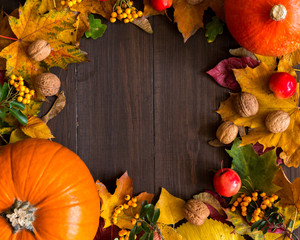 Dynie z liśćmi, orzechami, jarzębiną i darami jesieni na drewnianym tle, miejsce na napis 