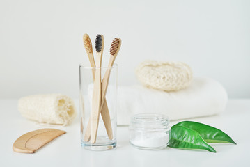 No plastic zero waste concept. Eco friendly wooden bamboo toothbrushes in a glass, towel, tooth powder and washcloth on white background