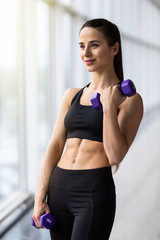 Young fitness woman exercising with weights in the gym