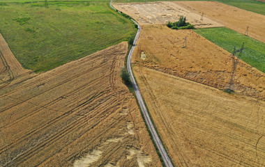 Aerial drone perspective on damaged wheat field after wind storm, rural landscape with asphalt road
