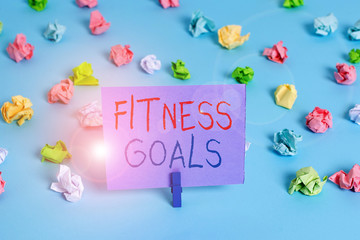 Word writing text Fitness Goals. Business photo showcasing Loose fat Build muscle Getting stronger Conditioning Colored crumpled papers empty reminder blue floor background clothespin