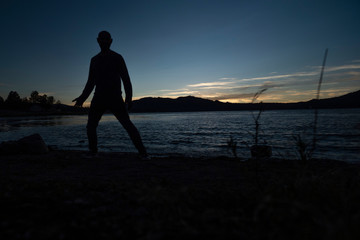 Fototapeta premium silhouette of a man during sunset next to lake