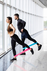 Attractive couple exercising with a resistance band in gym