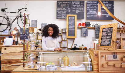 Smiling African American barista standing behind a cafe counter