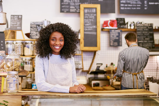 Smiling young African American entrepreneur working behind her cafe counter