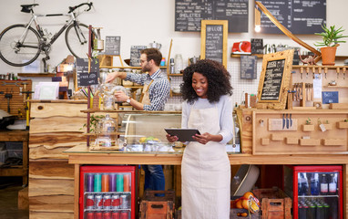 Young African American barista using a tablet in her cafe