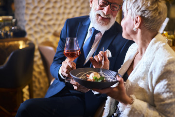 Caucasian man in suit and eyeglasses, beautiful woman in white elegant blazer enjoy meal in...