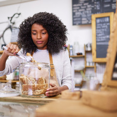 African American barista selecting a biscuit from a cafe jar