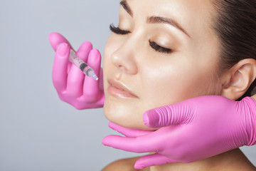 The doctor cosmetologist makes Lip augmentation procedure of a beautiful woman in a beauty...