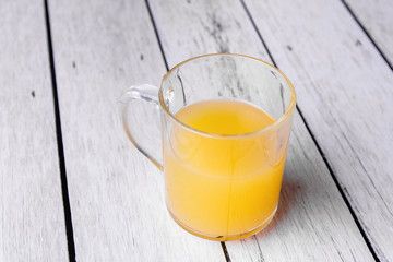 Half cup of orange juice on a white wooden background